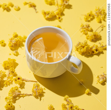 Herbal tea with immortelle and lemon in a white cup on a yellow background close up. Herbal tea with immortelle and lemon in a white cup on a yellow background close up. 119859968
