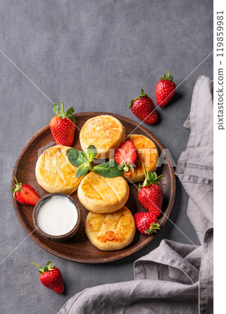 Cottage cheese, cheesecakes or syrniki with sour cream, strawberries and mint leaves  119859981