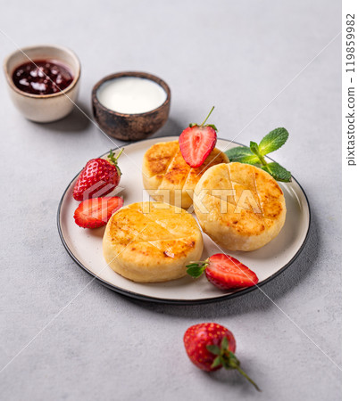 Cottage cheese, cheesecakes or syrniki with strawberries and mint leaves on a white plate Cottage cheese, cheesecakes or syrniki with strawberries and mint leaves on a white plate 119859982