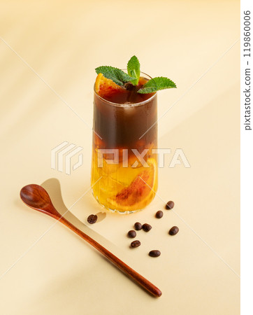 Americano coffee with orange juice (bumble) in a tall glass with ice and mint on a yellow background 119860006