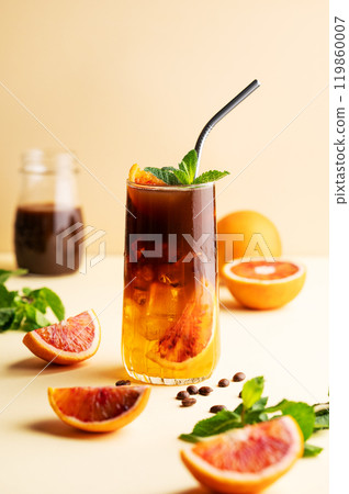 Americano coffee with orange juice (bumble) in a tall glass with ice and mint on a yellow background 119860007