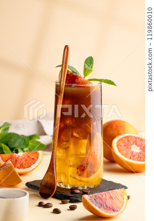Espresso coffee with orange juice (bumble) in a tall glass with ice and mint on a yellow background Espresso coffee with orange juice (bumble) in a tall glass with ice and mint on a yellow background 119860010