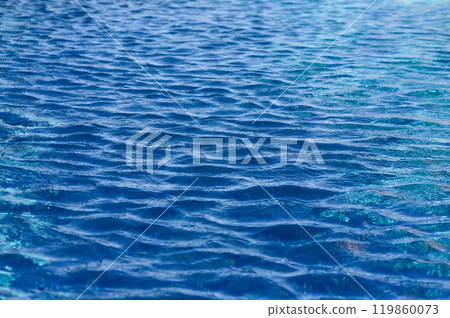 Gentle ripples dance on the surface of a crystal-clear blue pool under the warm afternoon sun 119860073