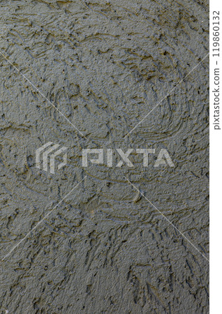 Textured surface of wet concrete at a construction site with gentle swirls and marks under natural light on a clear day 119860132