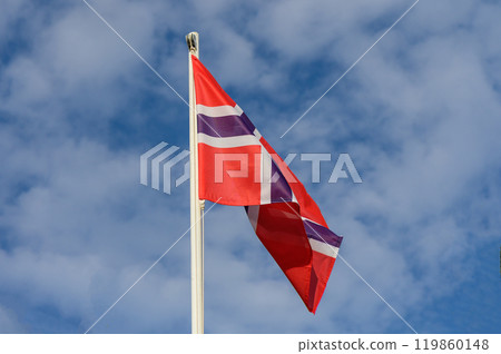 Colorful Norwegian flag waving under a bright blue sky with fluffy clouds during a sunny day in Norway Colorful Norwegian flag waving under a bright blue sky with fluffy clouds during a sunny day in Norway 119860148