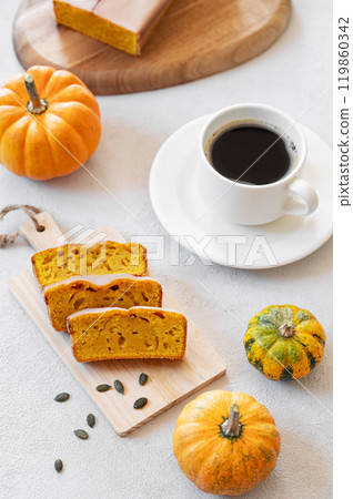 Pumpkin sweet bread or cake with icing on a plate on a light background with decorative pumpkins 119860342