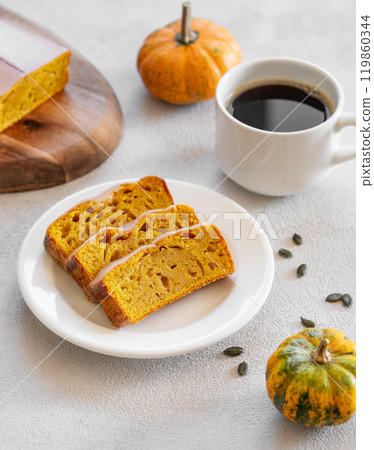 Pumpkin sweet bread or cake with icing on a plate on a light background with decorative pumpkins Pumpkin sweet bread or cake with icing on a plate on a light background with decorative pumpkins 119860344