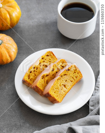 Slices of pumpkin sweet bread or cake with icing on a plate on a dark background  119860350