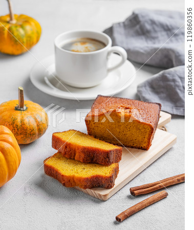 Pumpkin sweet bread with cinnamon on a wooden board on a light background with decorative pumpkins Pumpkin sweet bread with cinnamon on a wooden board on a light background with decorative pumpkins 119860356