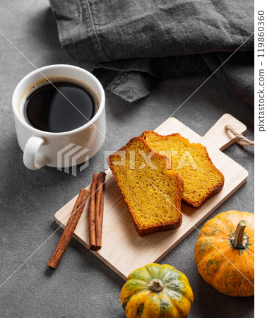 Slices of pumpkin sweet bread with cinnamon on a wooden board on a dark background Slices of pumpkin sweet bread with cinnamon on a wooden board on a dark background 119860360