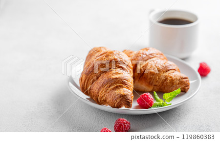 Cup of espresso coffee and croissants with fresh raspberries and mint on a plate  119860383