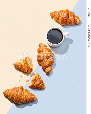 Flat lay of espresso coffee cup and fresh croissants on yellow and blue background with shadow. 119860398