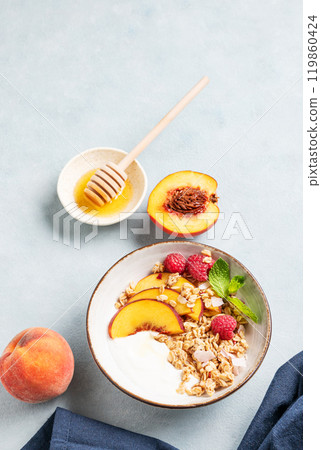 Greek natural yogurt with oat granola or muesli, peach, raspberry and honey in a bowl Greek natural yogurt with oat granola or muesli, peach, raspberry and honey in a bowl 119860424