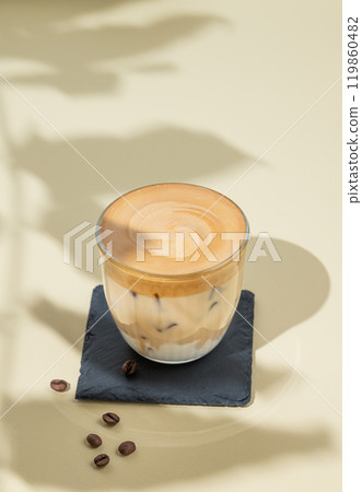 Dalgona coffee. Whipped instant coffee in a glass with ice on a yellow background with coffee beans 119860482