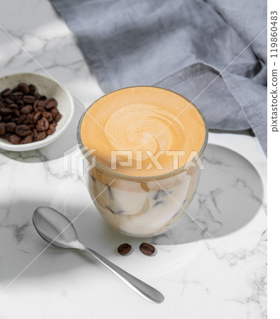 Dalgona coffee. Whipped instant coffee in a glass with ice on a marble background with coffee beans 119860483