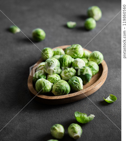 Fresh raw brussels sprouts in a wooden plate on a dark background close up. 119860560