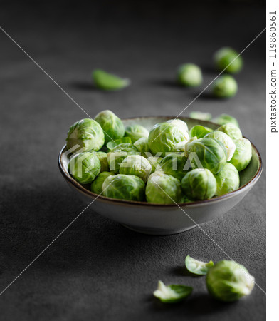 Raw brussels sprouts in a bowl on a dark background with fresh vegetables close up. Raw brussels sprouts in a bowl on a dark background with fresh vegetables close up. 119860561