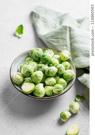 Fresh brussels sprouts in a bowl on a light gray background with green napkin.  119860563
