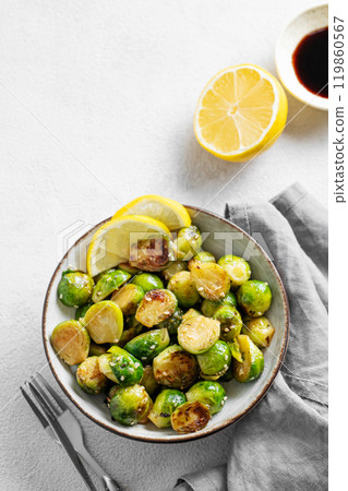 Fried brussels sprouts in a bowl with soy or balsamic sauce, lemon and sesame on a light background Fried brussels sprouts in a bowl with soy or balsamic sauce, lemon and sesame on a light background 119860567