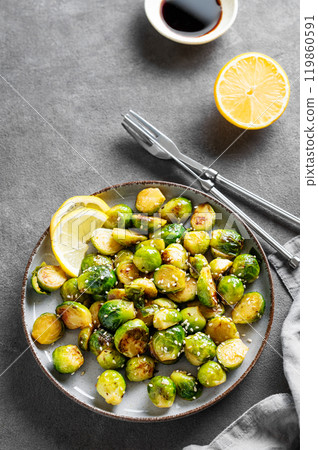 Crispy brussels sprouts in a plate with soy or balsamic sauce and sesame on a dark background Crispy brussels sprouts in a plate with soy or balsamic sauce and sesame on a dark background 119860591
