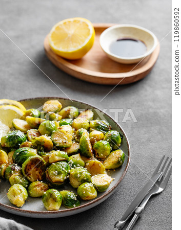 Crispy brussels sprouts in a plate with soy or balsamic sauce and sesame on a dark  background  119860592