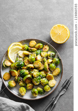 Fried brussels sprouts in a plate with soy or balsamic sauce and sesame on a dark  background 119860593