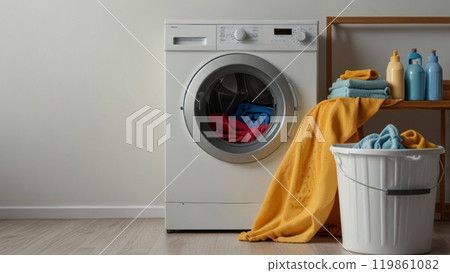 The washing machine sits prominently surrounded by various detergent bottles and a wicker laundry basket, emphasizing organization and cleanliness. 119861082
