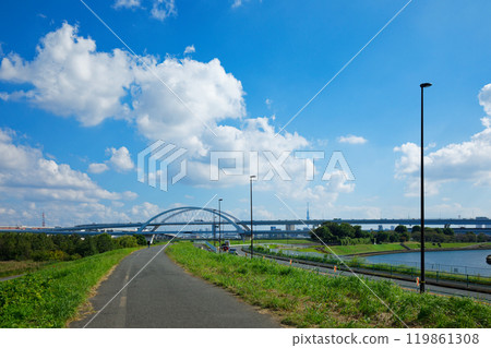 View of Goshikizakura Bridge and Kohoku Junction from the banks of the Arakawa River. White clouds in a blue sky. 119861308