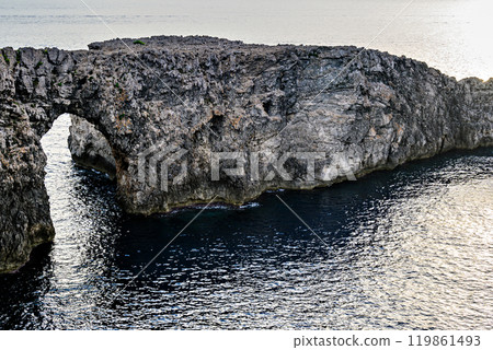 Spectacular sunset at Pont den Gil (Cala Corbetar) in Ciutadella, Menorca, Balearic Islands. Peculiar natural formation in the form of an arch Spectacular sunset at Pont den Gil (Cala Corbetar) in Ciutadella, Menorca, Balearic Islands. Peculiar natural formation in the form of an arch 119861493