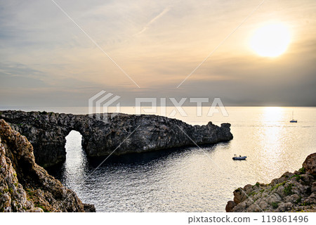 Spectacular sunset at Pont den Gil (Cala Corbetar) in Ciutadella, Menorca, Balearic Islands. Peculiar natural formation in the form of an arch Spectacular sunset at Pont den Gil (Cala Corbetar) in Ciutadella, Menorca, Balearic Islands. Peculiar natural formation in the form of an arch 119861496