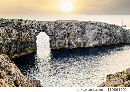 Spectacular sunset at Pont den Gil (Cala Corbetar) in Ciutadella, Menorca, Balearic Islands. Peculiar natural formation in the form of an arch 119861501