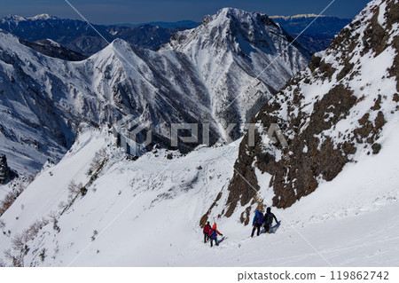 Climbers walking along the Yokodake ridgeline of the Yatsugatake mountain range in midwinter and a view of Amidadake 119862742
