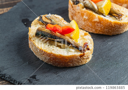 fish sandwiches with lemon on a stone board on the table. selective focus 119863885