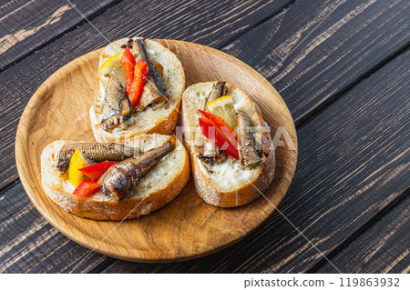 fish sandwich with butter and sprats lemon and red pepper on a dark table 119863932
