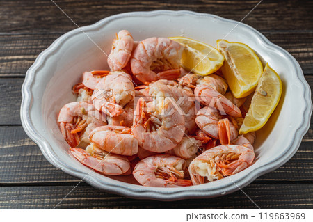 Boiled king prawns in deep bowl with lemon close up view on dark table Boiled king prawns in deep bowl with lemon close up view on dark table 119863969