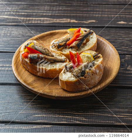 fish sandwich with butter and sprats lemon and red pepper on a dark table 119864014