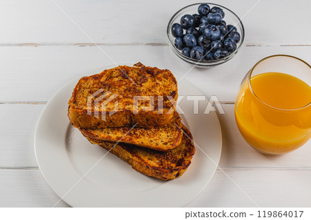 French toast on a white plate with blueberries and orange juice for breakfast 119864017