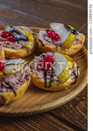 toast with chicken liver pate with pear, cranberry and sauce on a wooden table 119864036