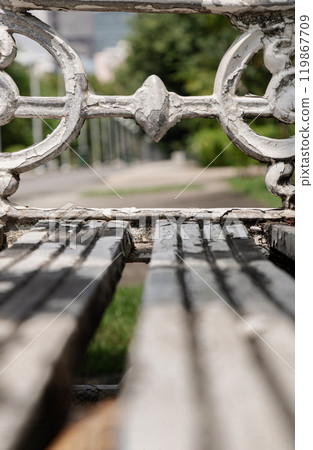 Close-up of White painted cast iron victorian style garden bench in city park. Close-up of White painted cast iron victorian style garden bench in city park. 119867709