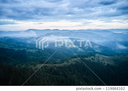 Mist-covered valley surrounded by lush, forested mountains. Winding river snakes through valley, and small villages dot landscape, creating serene and tranquil atmosphere. Mist-covered valley surrounded by lush, forested mountains. Winding river snakes through valley, and small villages dot landscape, creating serene and tranquil atmosphere. 119868102