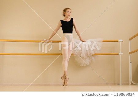 Ballet dancer standing on pointe at barre, holding tutu Ballet dancer standing on pointe at barre, holding tutu 119869024