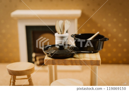 Black pots and wooden utensils in a warm kitchen 119869150