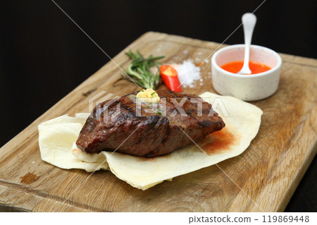 Medium rare steak placed on pita bread on a special wooden board. Beef steak on a wooden board. 119869448