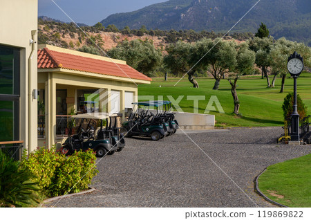 A picturesque golf course in the mountains with parked golf carts on a stone pathway under bright sunny skies 119869822