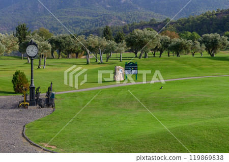 A tranquil morning on the golf course with lush greenery and a vintage clock in a serene landscape A tranquil morning on the golf course with lush greenery and a vintage clock in a serene landscape 119869838