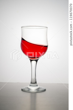 Red wine splashing in glass against white background. Copy space. 119870070