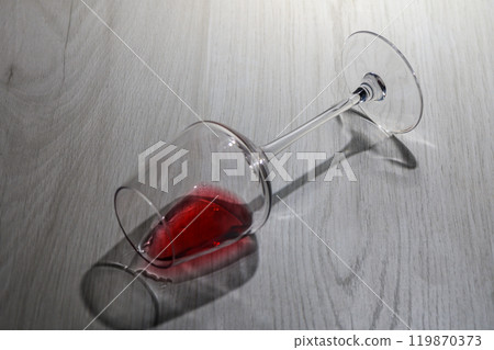 Concept of alcoholism A glass of red wine lies on its side on the table. Concept of alcoholism A glass of red wine lies on its side on the table. 119870373
