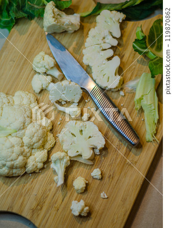 Fresh cauliflower and leaves on wooden chopping board and metal knife . High quality photo Fresh cauliflower and leaves on wooden chopping board and metal knife . High quality photo 119870862