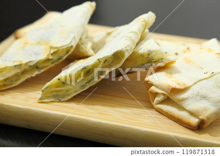 Lavash with baked cheese. Lavash with baked cheese on a wooden board. Lavash with cheese. Lavash with baked cheese. Lavash with baked cheese on a wooden board. Lavash with cheese. 119871318