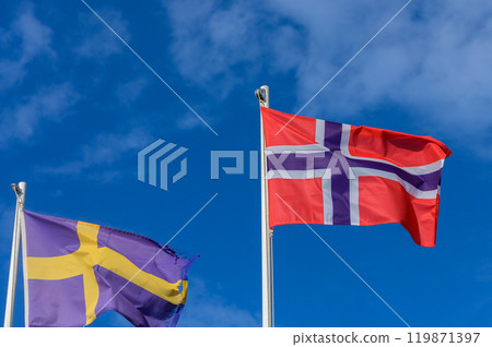 Flags of Norway and Sweden billow against a brilliant blue sky on a sunny day, representing unity and shared heritage in Northern Europe Flags of Norway and Sweden billow against a brilliant blue sky on a sunny day, representing unity and shared heritage in Northern Europe 119871397